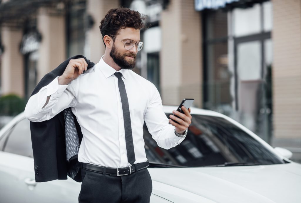 portrait young successful handsome man suit background new white car reading mail his smartphone 1